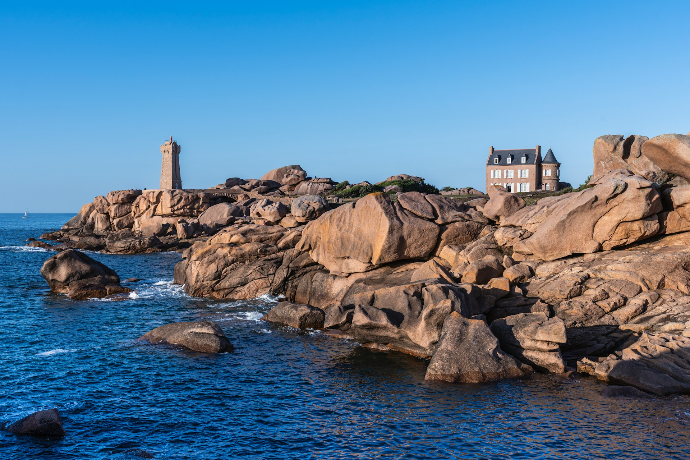 a house on top of a rock outcropping next to the ocean