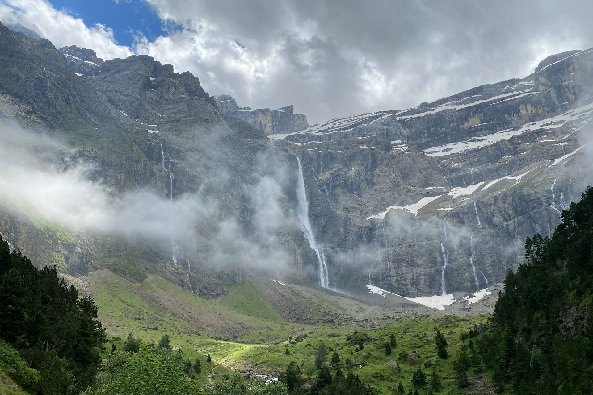 green trees near mountain under white clouds during daytime